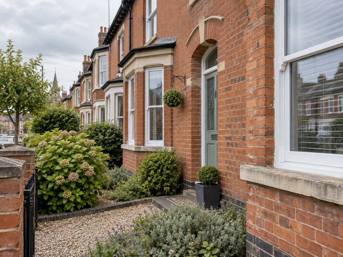 Traditional Northampton red-brick terrace with weathered mortar joints along a quiet residential street and front garden.