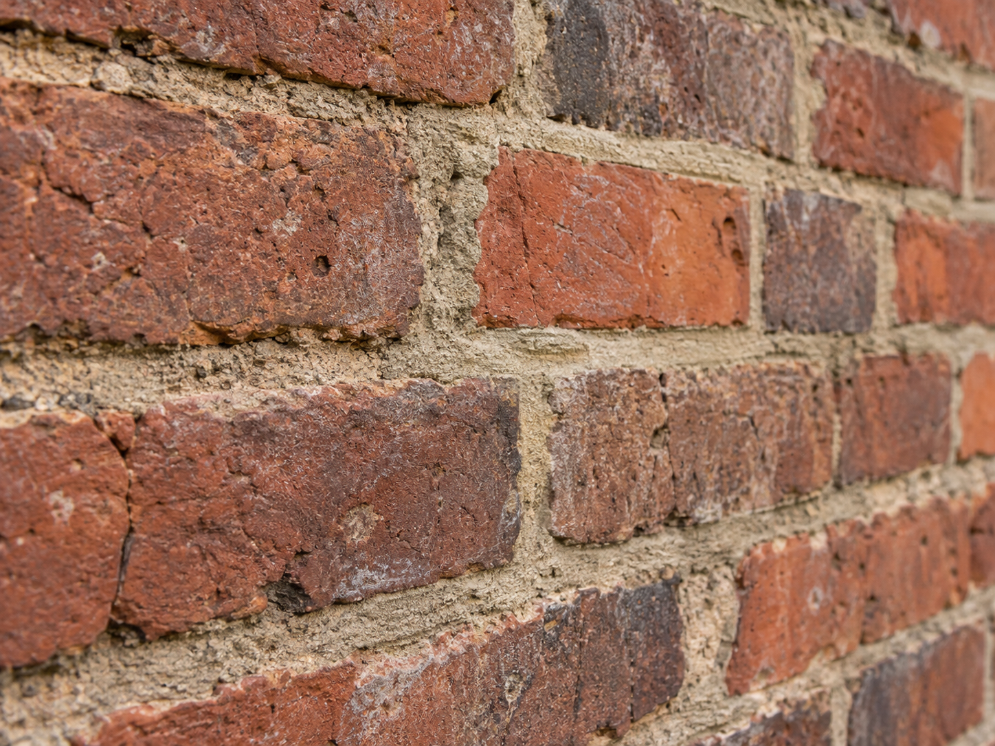 Close architectural view of porous historic red brick and softer mortar joints showing authentic texture and weathering.